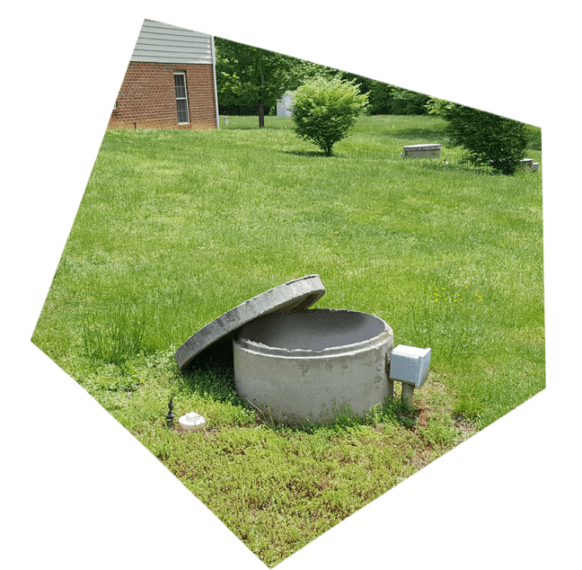 A picture of an open septic tank in the grass.